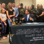 Gov. Ron deSantis turns to Emma Stanford, who is between Sen. Travis Hutson and Sheriff Rick Staly, at the bill signing this morning at the Flagler County Courthouse. Rep. Ki (© Emma Stanford for FlaglerLive)