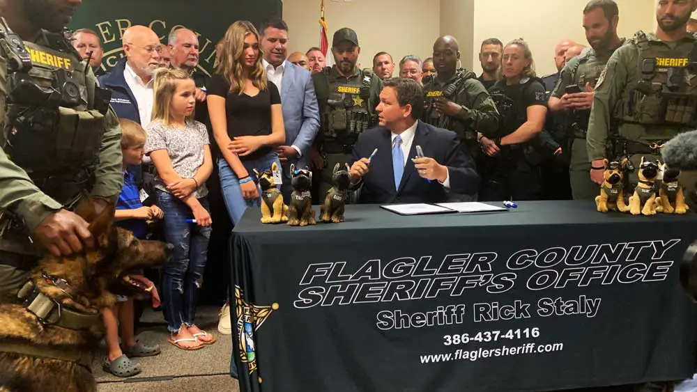 Gov. Ron deSantis turns to Emma Stanford, who is between Sen. Travis Hutson and Sheriff Rick Staly, at the bill signing this morning at the Flagler County Courthouse. Rep. Ki (© Emma Stanford for FlaglerLive)