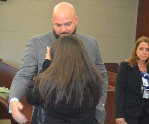 Flagler Sheriff's detective George Hristakopoulos comforting the victim after the sentence, with detective Annie Conrad to the right. Both detectives had worked the case since 2017. (© FlaglerLive)