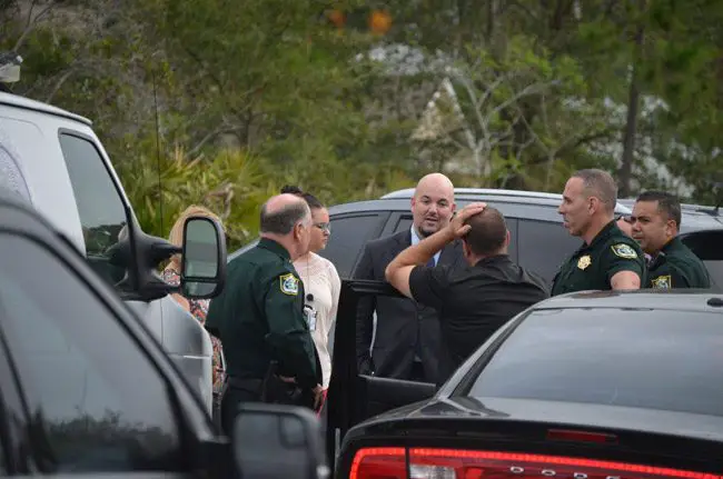 Flagler County Sheriff's detective George Hristakopoulos, center, with Sheriff Rick Staly, left, and other members of the sheriff's office outside of the Seamanship Trail house the morning of the shooting there that resulted in two young men being hospitalized, but no charges yet from that particular shooting. Evidence gathered from the scene, however, resulted in unrelated charges against one of the victims and suspects, Tristan George, now 19. (© FlaglerLive)