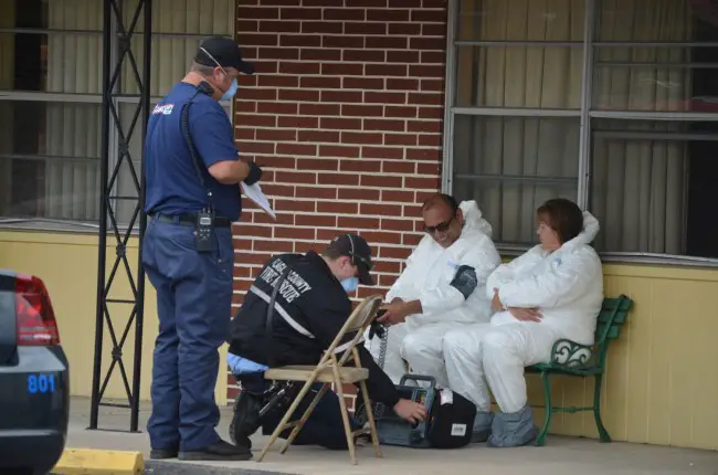 The motel owner known as D.J. and one of the motel's cleaning ladies, Carol, being tended to outside a room at the motel early this afternoon. (c FlaglerLive)