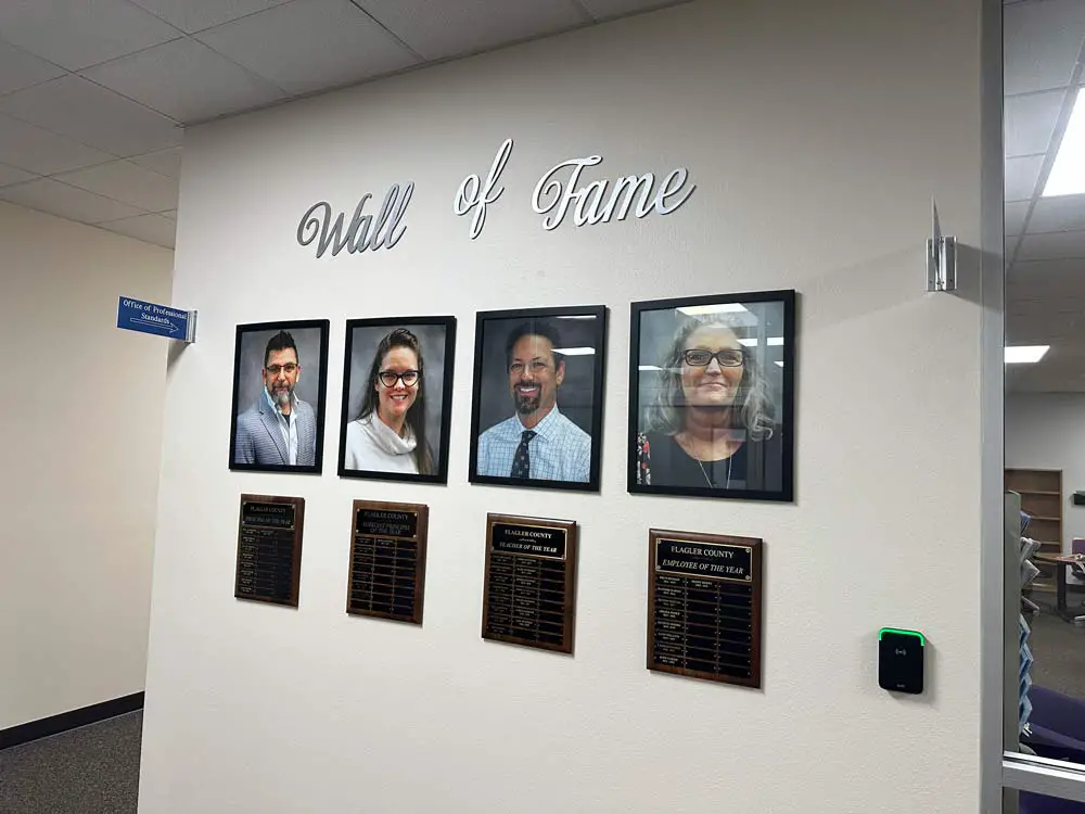 Donelle Evensen's portrait and recognition plaque, second from left, as the reigning assistant principal of the year, on the district's Wall of Fame outside the superintendent's suite at the Government Services Building. (© FlaglerLive)
