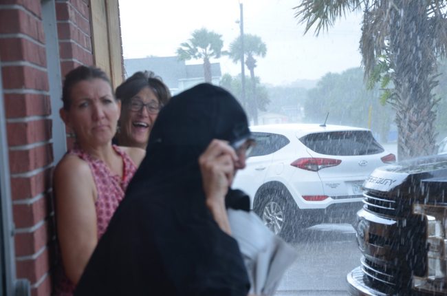 Anna Hackett, center, and others caught in a pre-Dorian downpour outside Swillersbees in Flagler Beach Sunday. (© FlaglerLive)