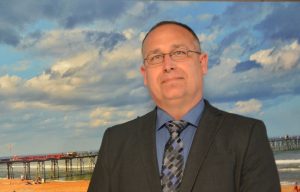 Dru Driscoll Wednesday evening, standing in front of Flagler Beach photographer and attorney Scott Spradley's photograph of the pier. (© FlaglerLive)