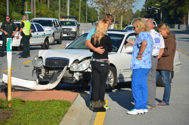 The young male driver in the blue shirt comforted his passenger, in black, in front of his Hyundai. Click on the image for larger view. (© FlaglerLive)