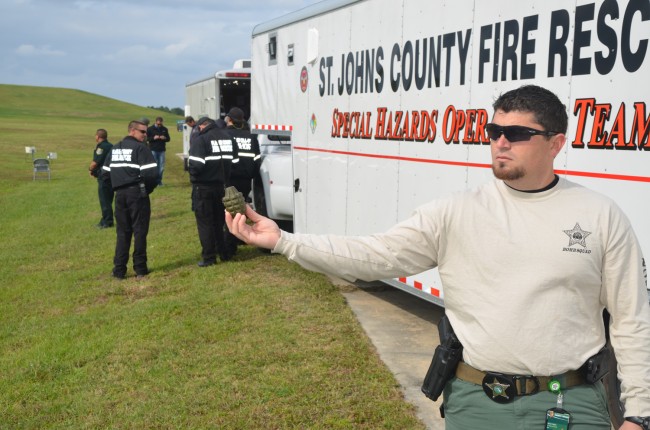 A member of the St. Johns County Sheriiff's Office's bomb squad shows the dud pineapple grenade found at the Flagler County landfill this morning. Click on the image for larger view. (© FlaglerLive)