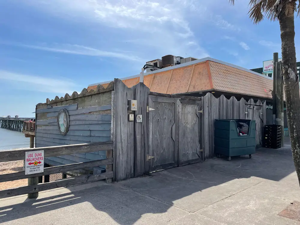 The dumpster enclosure outside the Funky pelican in Flagler Beach has needed repairs for years. The city commission voted to award a bid for those repairs. It did not know that it was also voting to expand the dumpster area, further blocking the view of the ocean to the north of the restaurant. (© FlaglerLive)