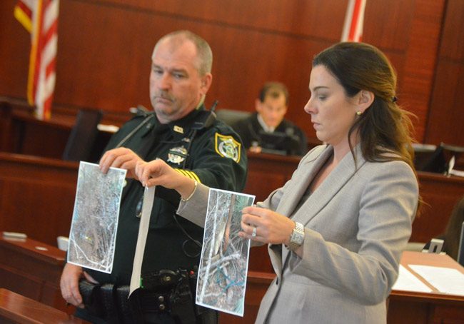 Assistant State Attorney Jennifer Dunton, with help from bailiff John Freshcorn, showed the jury pictures of the wooded area that had looked odd to a detective, and that proved to be the makeshift grave Dorothy Parker dug for her husband, Charles Singer, after killing him in February 2017 in west Flagler. (© FlaglerLive)