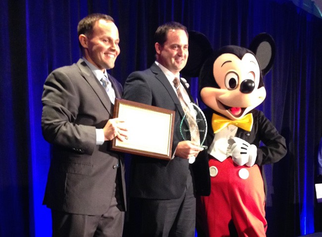 Deputy Chancellor for Educator Quality Brian Dassler, left, gave Dustin Sims the Florida Assistant Principal of the Year  award at the Coronado Springs Resort this afternoon, with Mickey Mouse, an honorary  IB graduate, looking on.  