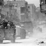 Israeli soldiers in armored vehicles drive through a Lebanese village in 1982.