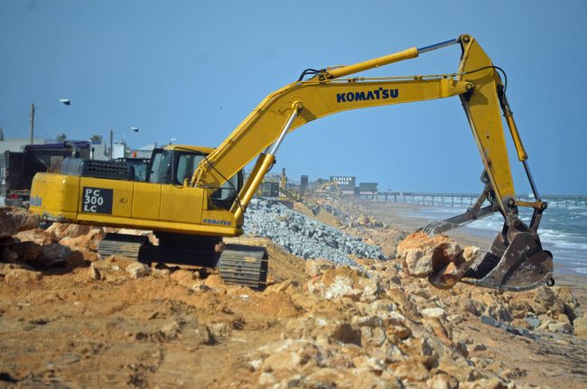 Three excavators were rebuilding the dunes on that portion of State Road A1A this afternoon, looking north toward the pier, with more to the south, as Halifax Paving, the contractor on the job, hurried to beat the 45-day deadline by 30 days, to re-open A1A next week. Click on the image for larger view. (© FlaglerLive)