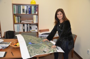 The hard hat at the top of the bookshelf is not just for show: Flagler County Engineer and Public Works Director Faith Alkhatib maps out innumerable local infrastructure projects without which the county could not function. (© FlaglerLive)