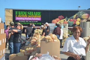 Mary King was among the 40-odd volunteers who gave out Farm Fresh's packaged food this morning at the Flagler County Airport. (© FlaglerLive)