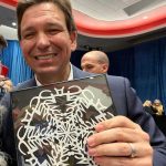 An apparently unaware Gov. Ron DeSantis, in Iowa to defend his culture war offensives, holds up what appears to be a snowflake gifted to him. A closer look reveals that the snowflake's arms are calligraphic versions of the word "Fascist." An Iowa Facebook page posted the picture with the following caption: "Little D Santis gets owned. My friend makes snowflakes to give to politicians who come to Iowa - there are special messages for odious Republicans--please look at the snowflake carefully 🤣😉"