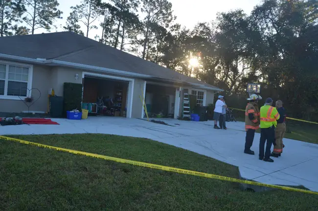 The owner of the house, Jessica Evans, is comforted by a friend, Richard price, the Palm Coast attorney, as Deputy Fire Chief Jerry Forte, right, speaks with Battalion Chief Ron Petrillo and Fire Police Captain Steve Garnes. (© FlaglerLive)