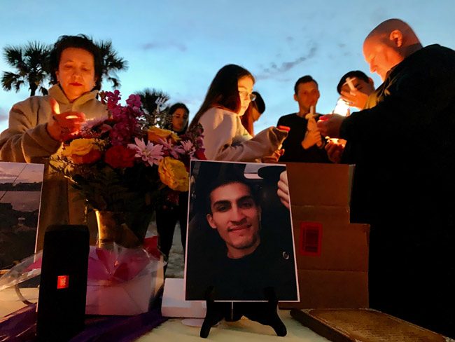 Anthony Fennick's friends and family members lighting up candles at his memorial on the beach last week. (© Shannon Trivino for FlaglerLive)