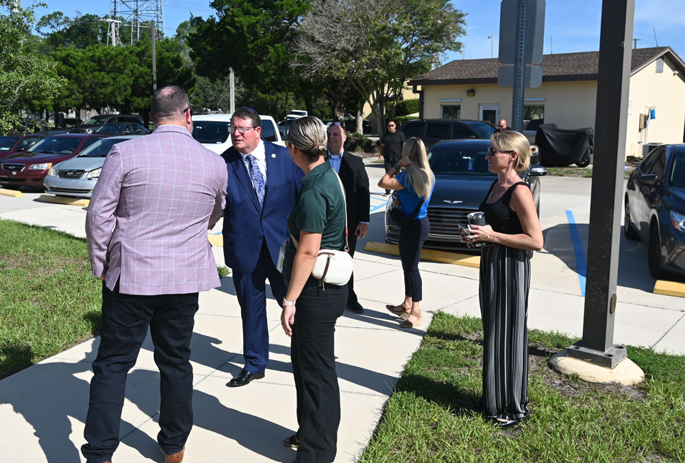 His glasses fogged up by condensation--he'd jus stepped out of an air-conditioned car into 90-degree heat--U.S. Rep. was greeted at the utility plant by Palm Coast Council member Theresa Pontieri, right, Council member Ty Miller, and Interim City Manager Lauren Johnston. (© FlaglerLive)