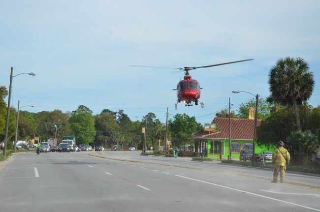 'Action Jackson,' more officially known as Jackson, a firefighter-paramedic with Flagler County Fire Rescue, guided Fire Flight off U.S. 1 in Downtown Bunnell Thursday afternoon as part of the evacuation of two trauma patients. A second patient was transported to Daytona Beach's Halifax hospital by ground. (© FlaglerLive)