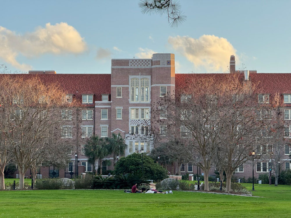 Students sit on blankets on Florida State University’s Landis Green on Dec. 31, 2024, with Landis Hall in the background. (Photo by Jay Waagmeester/Florida Phoenix)