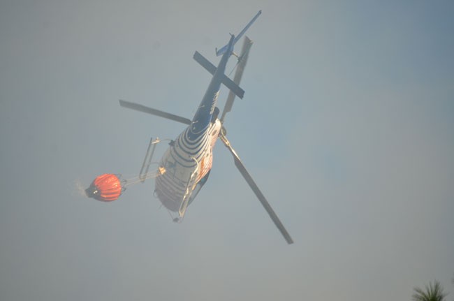 Fire Flight flew in the thick of the smoke to drop its water loads. (c FlaglerLive)