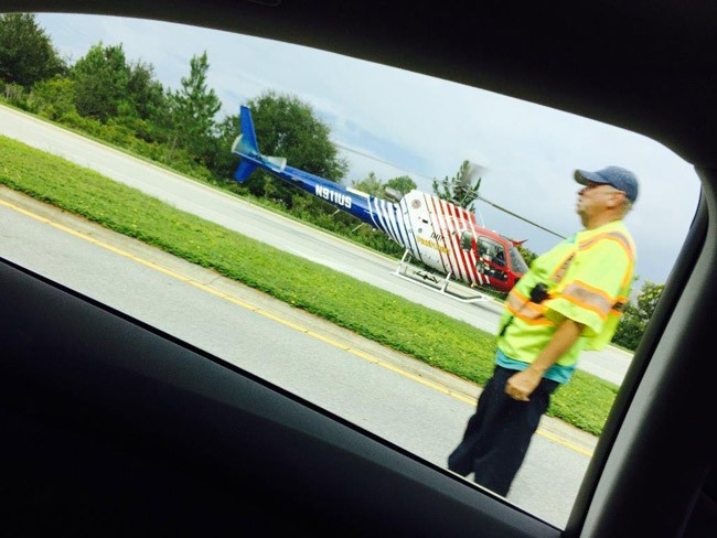 A reader took that  perfect frame of Flagler County Fire Flight, the emergency helicopter, when it made a landing on Belle Terre Parkway Monday afternoon during the emergency started by the single-vehicle car wreck involving Palm Coast resident Peter Slusarz. That's Steve Garnes, captain of the Palm Coast Fire Police, to the right. (© FlaglerLive)