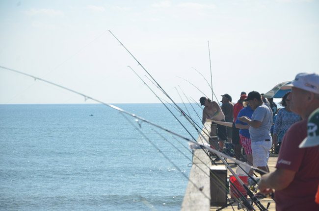 The Flagler Beach Pier's fishermen paid little attention to the ribbon-cutting at the entrance to the structure on Saturday. (© FlaglerLive)