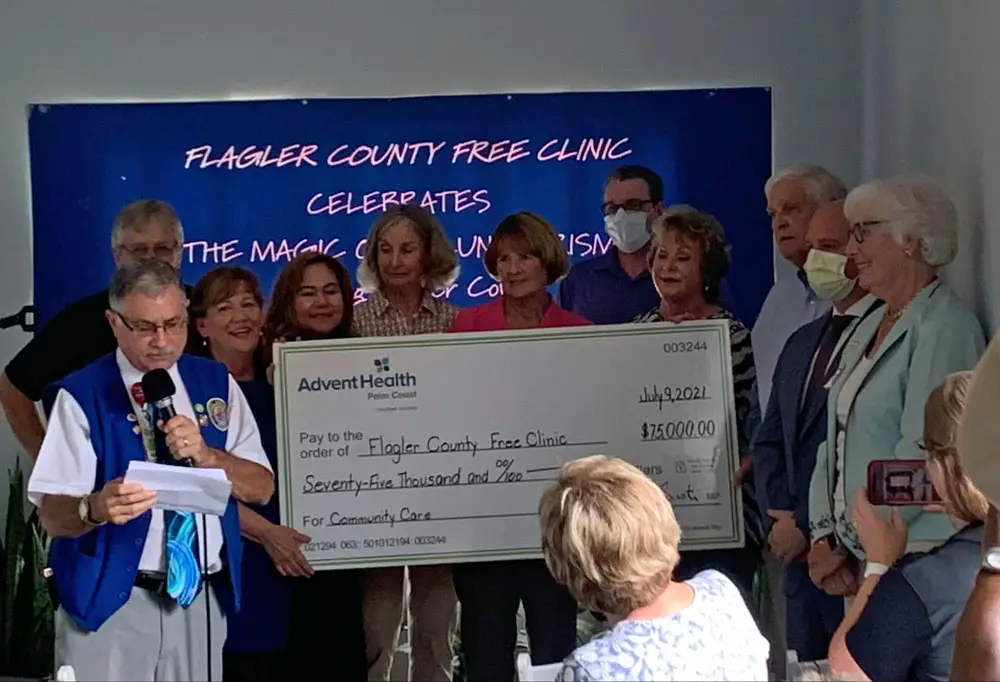 Tom Sisti of the AdventHealth Auxiliary gifting the Free Clinic the big check. (© FlaglerLive)
