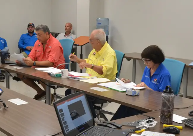 Florence Fruehan, in the orange shirt, at an East Flagler Mosquito Control District meeting in 2017, with board members Julius Kwiatkowski and Barbara Sgroi. (c FlaglerLive)