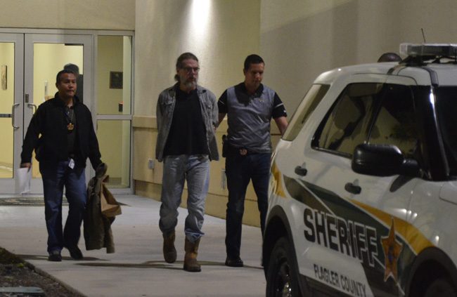 Michael Cummings being led out to a patrol car, on his way to the county jail this evening, flanked by detectives Mark Moy, left, and Jorge Fuentes, who worked the case. (c FlaglerLive)