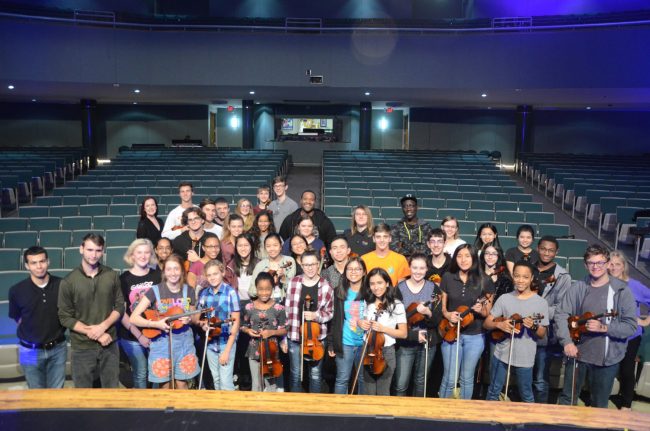 Black Violin duo members Kev Marcus and Wil B, in the rear row, gave members of the Flagler Youth Orchestra's Harmony ensemble a special hour-long master class Monday before Black Violin's 7:30 p.m. performance at the Flagler Auditorium. Marcus invited several of the students on stage to improvise and told them all to follow their passion if they want to end up like him--doing what he loves most nights of the year on stage. Monda's was Black Violin's last performance of the year. (© FlaglerLive)