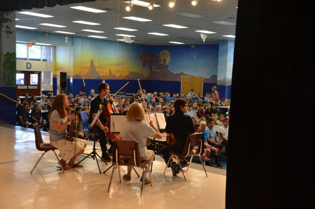 The Flagler Youth Orchestra Quartet was in performance at Old Kings Elementary before third and fourth graders, part of its annual recruiting tour through district schools. The quartet also performed today at Bunnell and Rymfire elementaries, and did so on Tuesday at Belle Terre Elementary and Wadsworth Elementary. Students are introduced to the free, district-supported after-school program and introduced to the various instruments they could play. Some 320 students have registered so far, with two weeks left in the enrollment period, which ends with an open house at Indian Trails Elementary on Sept. 6. (© FlaglerLive)