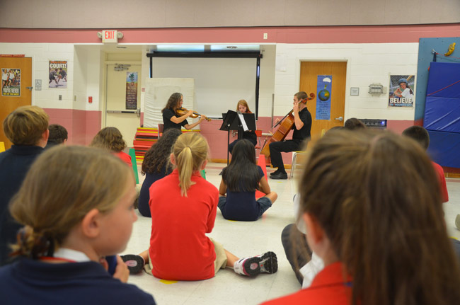 Fifth graders at Wadsworth Elementary heard a Flagler Youth Orchestra trio--Caren Umbarger, Mary Thopson and Austin Smith--play them the sort of music they;d be able to play after a few years in the program. (© FlaglerLive)