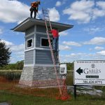 A couple of workers were adding a few touches to the symbolic tower at what will be one of the entrances to The Gables development of single-family homes in Town Center, adjacent to, and going well beyond, Imagine School at Town Center. (© FlaglerLive)