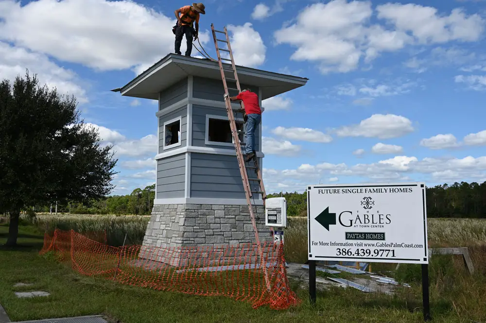 A couple of workers were adding a few touches to the symbolic tower at what will be one of the entrances to The Gables development of single-family homes in Town Center, adjacent to, and going well beyond, Imagine School at Town Center. (© FlaglerLive)
