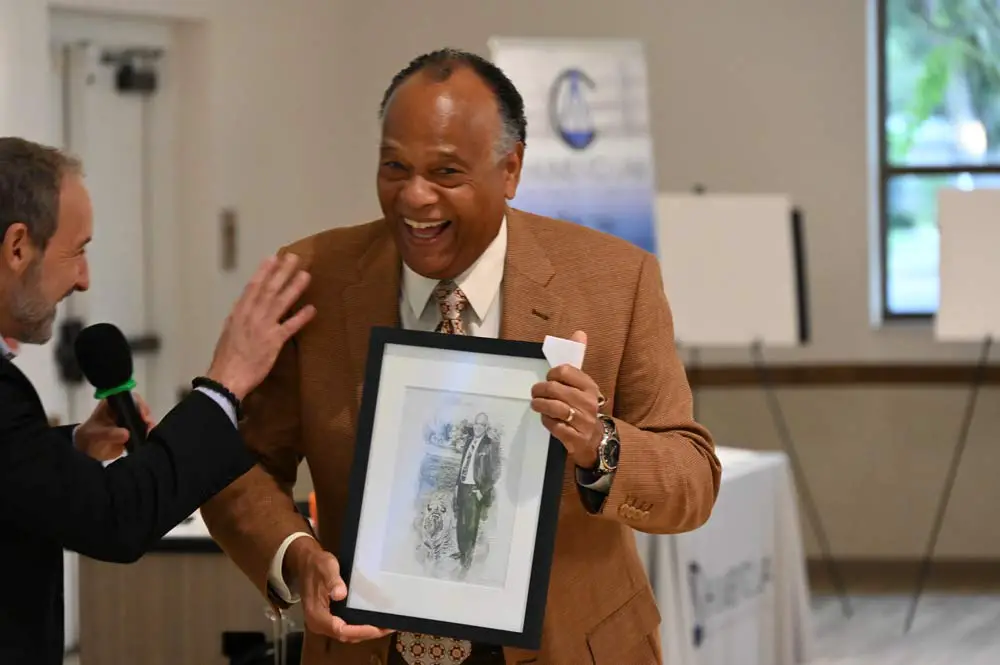 One of the club's gifts to Greg Davis, right, is a drawing of Davis with a tiger. Jay Scherr is at left. (© FlaglerLive)
