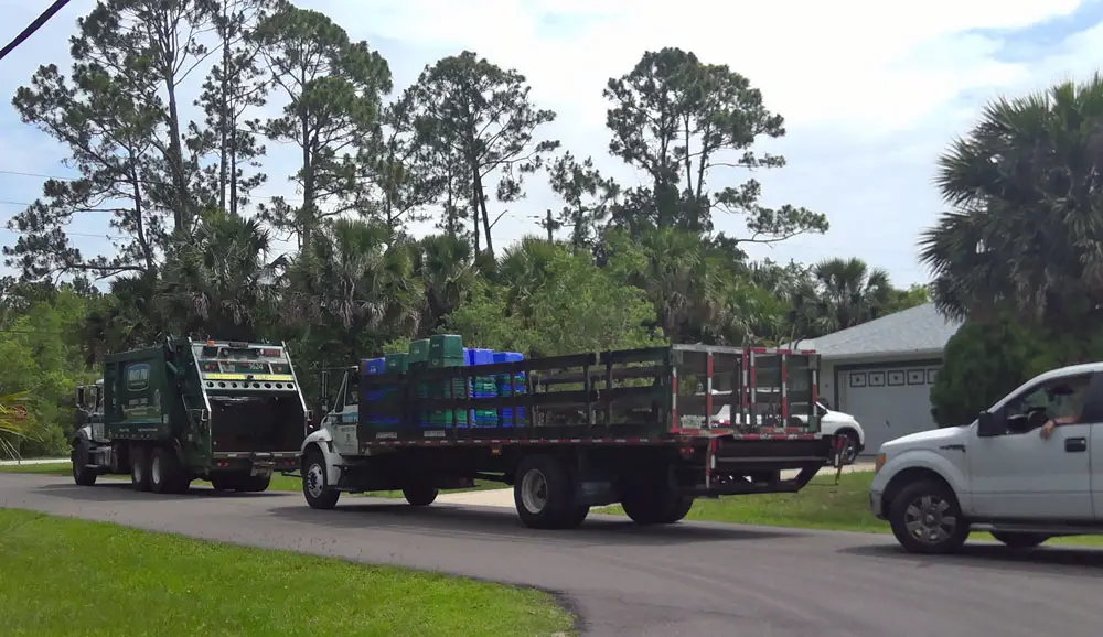A Waste Pro recycling truck followed by a flatbed truck in a Palm Coast neighborhood today, where the company's workers stacked residents' emptied recycling bins to haul away. (Palm Coast)