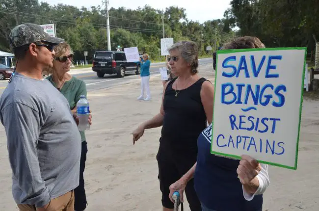 Captain's BBQ co-owner Chris Herrera, left, at the beginning of a long exchange with Barbara Royer during the protest. (© FlaglerLive)