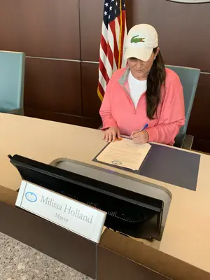 Mayor Milissa Holland signing a state of emergency proclamation earlier today. It was not sponsored by Lacoste. (Palm Coast)