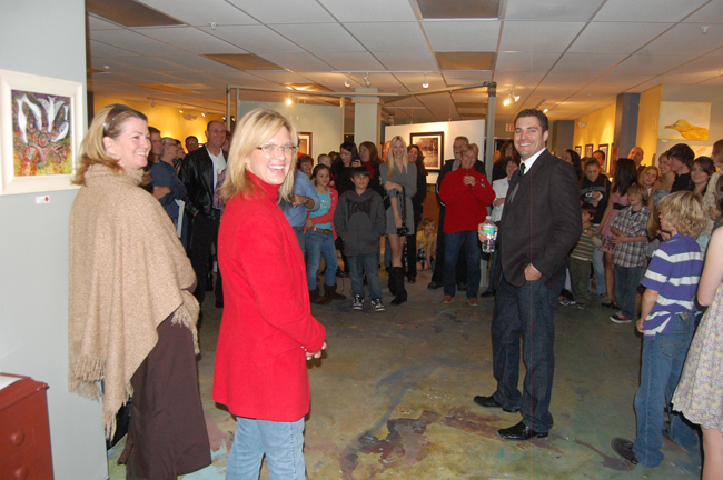 Photographer A.J. Neste, center, Heather Beaven (in red) and Colleen Conklin (right), presenting the one-night-only-showing of 15 young photographers at Hollingsworth Gallery Thursday. (© FlaglerLive)