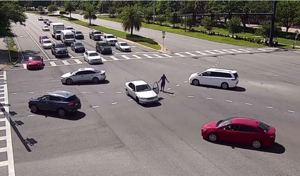 Christopher Holmes, his car stopped in the middle of the intersection, walked around gesturing. It was one amid a series of bizarre and criminal incidents Thursday afternoon. (© FlaglerLive via FCSO video)