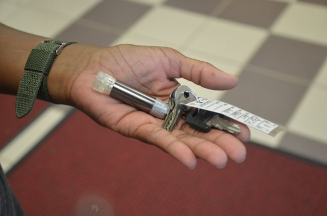 A formerly homeless woman at the library grounds shows the key to her camper, donated and secured at Thunder Gulch campground. (© FlaglerLive)