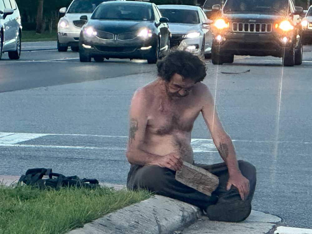 A homeless man on State Road 100 and Old Kings Road in Palm Coast. (© Pierre Tristam/FlaglerLive)