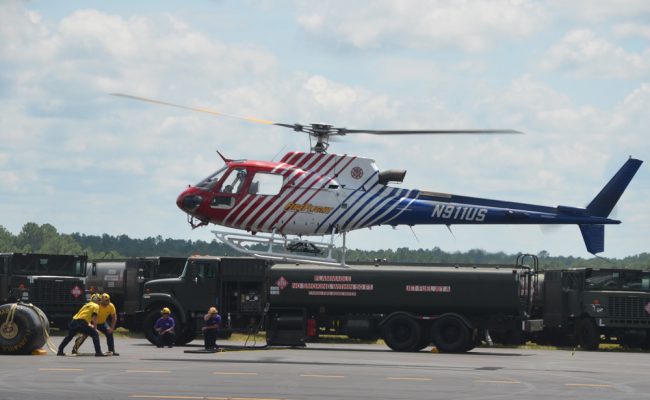 Flagler County's Fire Flight emergency helicopter during a demonstration of a 'hot refueling' maneuver with Kimble’s Aviation Logistical Services at the airport last week, when an aircraft is refueled without turning off engines. The maneuver is intricate but used during critical emergency operations in the aftermath of disasters. (© FlaglerLive)