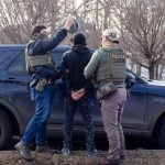 ICE agents search the passenger of a truck as they arrest both him and the driver during a traffic stop in February in Robbinsdale, Minn. Almost a quarter of ICE arrests in recent months have been “collateral,” a category that has raised legal questions, rather than “targeted” arrests based on preexisting warrants or removal orders. (Photo by Nicole Neri/Minnesota Reformer)