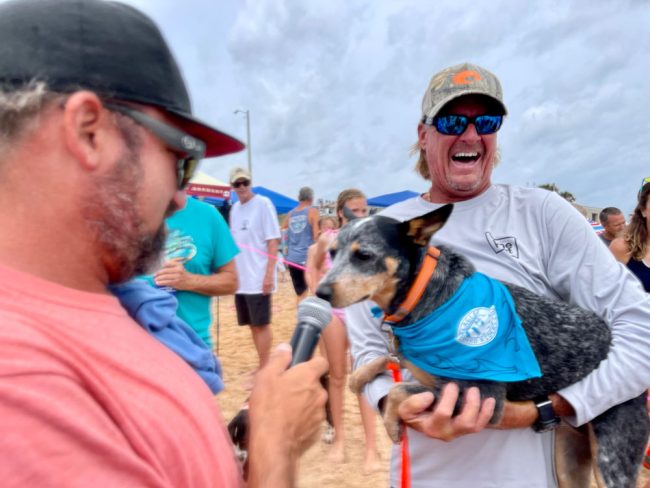 Emcee Travis Ajay interviewing one of the competitors, with Bob Lindsley, a celebrated surfer. (© AJ Neste for FlaglerLive)