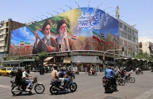 People ride motorcycles past a large billboard in central Tehran on June 8, 2026.