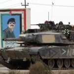A U.S. tank moves past a painting of Saddam Hussein in March 2003 in Nasiriyah, Iraq. (Joe Raedle/Getty Images)