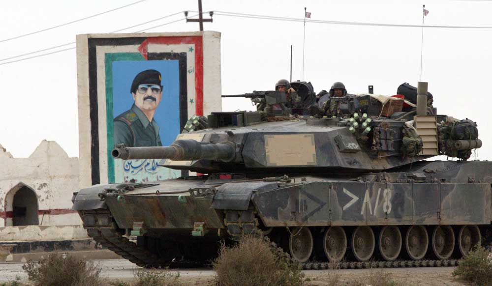 A U.S. tank moves past a painting of Saddam Hussein in March 2003 in Nasiriyah, Iraq. (Joe Raedle/Getty Images)