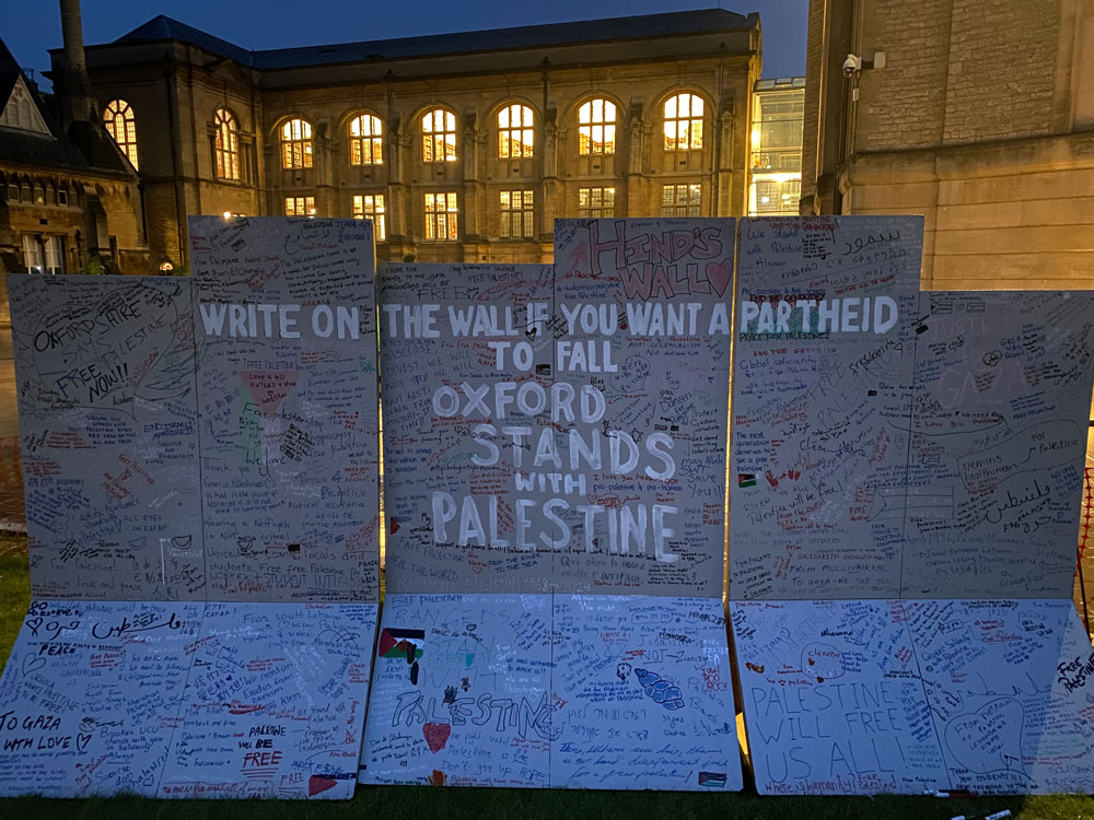 https://flaglerlive.com/wp-content/uploads/File-Night-photograph-of-the-2024-Oxford-Palestine-solidarity-encampment-13-jpg-Wikimedia-Commons-07-30-2025_04_36_PM.pdf Visible in this image is an artist's recreation of the West Bank apartheid wall which guests of the encampment are invited to draw on. In the background are buildings belonging to Reuben College and the Bodleian Library's Radcliffe Science Library.