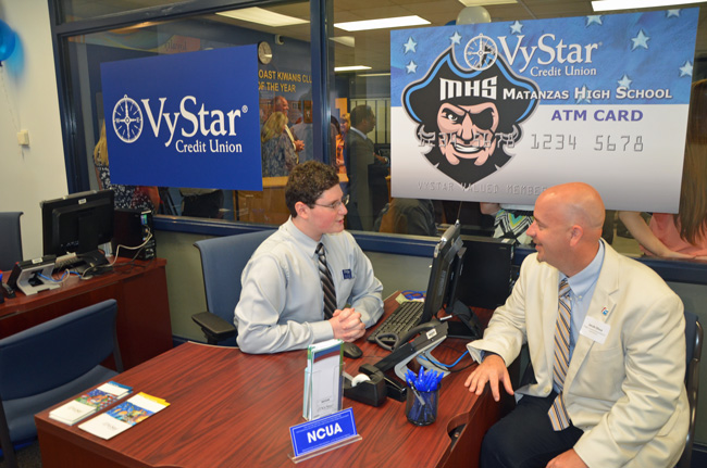 Flagler School Superintendent Jacob Oliva was the Matanzas High School VyStar branch's first customer today, opening a credit union account as student-employee Fred Beyder, a junior, walked him through the process. (© FlaglerLive)